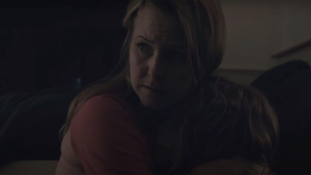 a blonde mom holding her daughter close to her with a scared face.