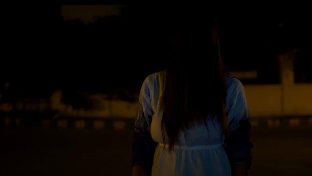 a strange women in white clothes with her hair in front of her face